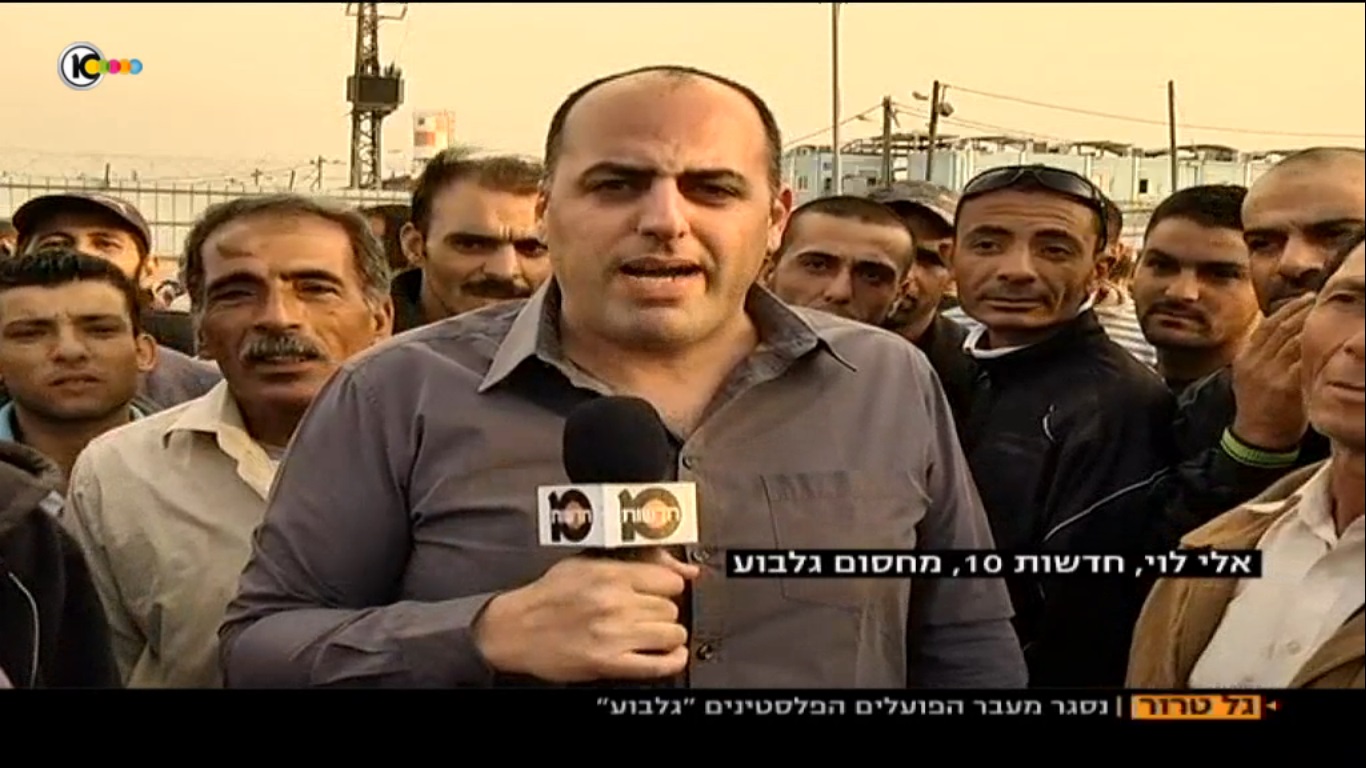 אלי לוי מוקף בפועלים ערבים (צילום מסך ערוץ 10)