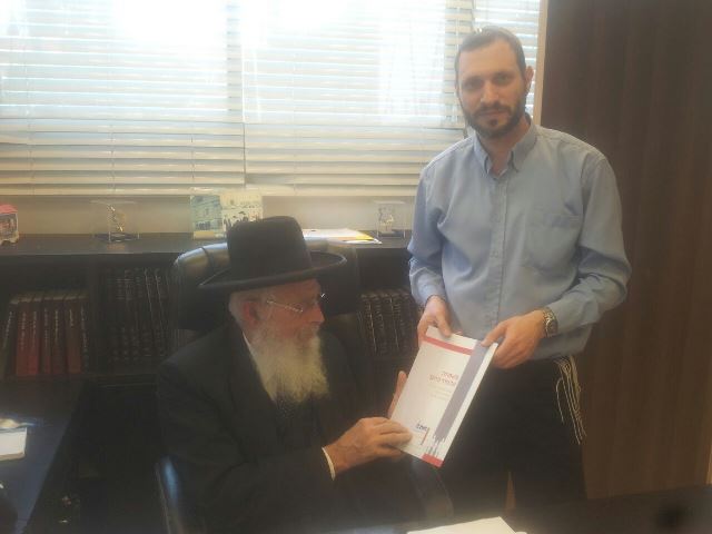 הרב יעקב אריאל מקבל לידיו את חוברת 'משפחה על סדר היום' (יחצנים)