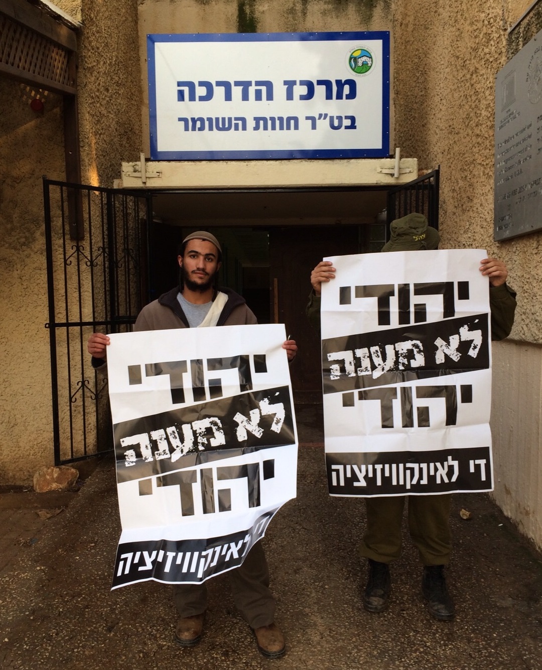 שריה כלף עם חייל נוסף נושאים שלטים 'יהודי לא מענה יהודי' בבסיס חוות השומר