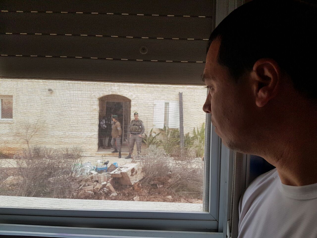 נתי פאר, שנפצע בצוק איתן וביתו מיועד היום להריסה, מביט בכוחות הגירוש מבעד לחלון ביתו (אהוד אמיתון, tps)